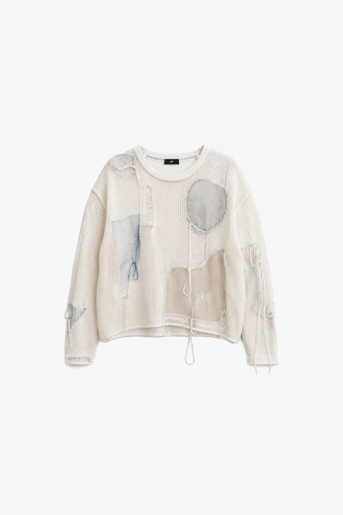 Ivory open-knit sweater laid flat, circular and rectangular fabric patches placed across the body