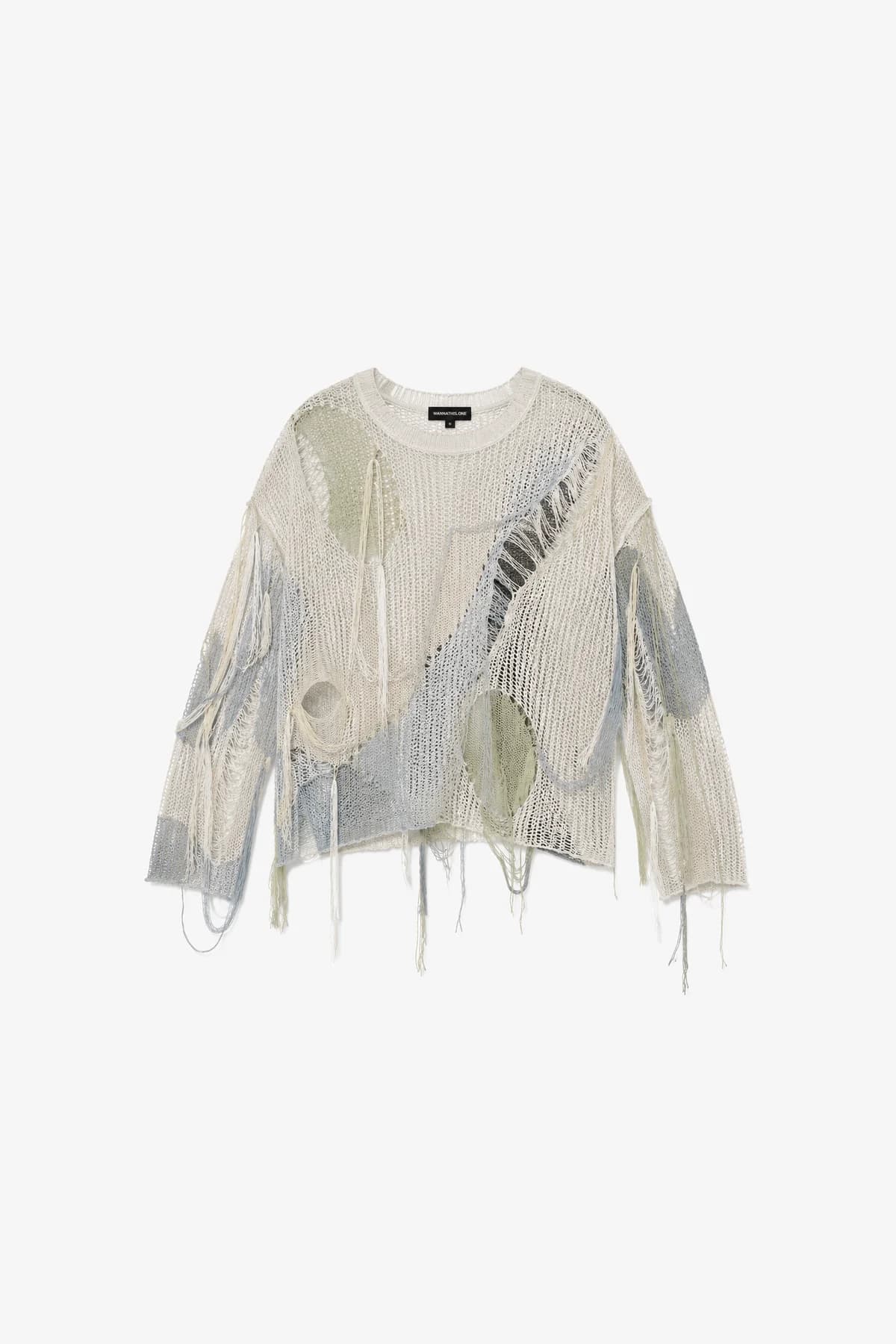 Pastel open-knit sweater laid flat, long frayed threads hanging from the hem and sleeves